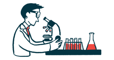 A researcher uses a microscope in a laboratory alongside a rack of test tubes and a beaker.