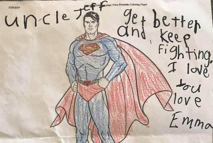 A child's coloring book image of Superman with a handwritten note that says, "Uncle Jeff, get better and keep fighting. I love you. Emma."