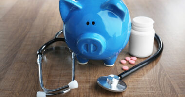 blue piggy bank with stethoscope and pill bottle