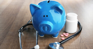 blue piggy bank with stethoscope and pill bottle