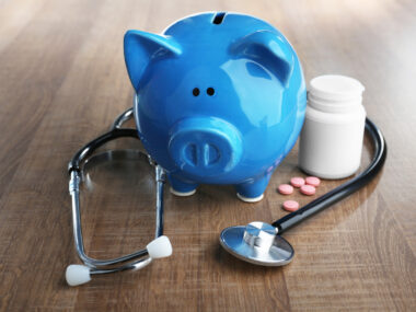 blue piggy bank with stethoscope and pill bottle