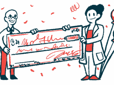 Two people, one in a lab coat, hold each end of an oversized check amid confetti and balloons.