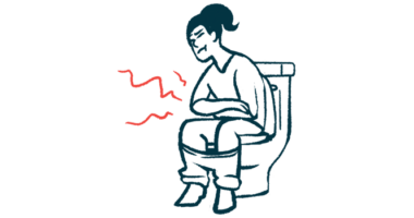 A woman sits on a toilet holding her stomach.