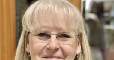 A very large close-up of a woman's face. She is smiling broadly.