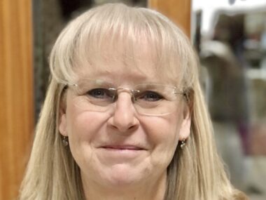 A very large close-up of a woman's face. She is smiling broadly.