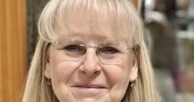 A headshot features an older woman with blond hair and glasses.