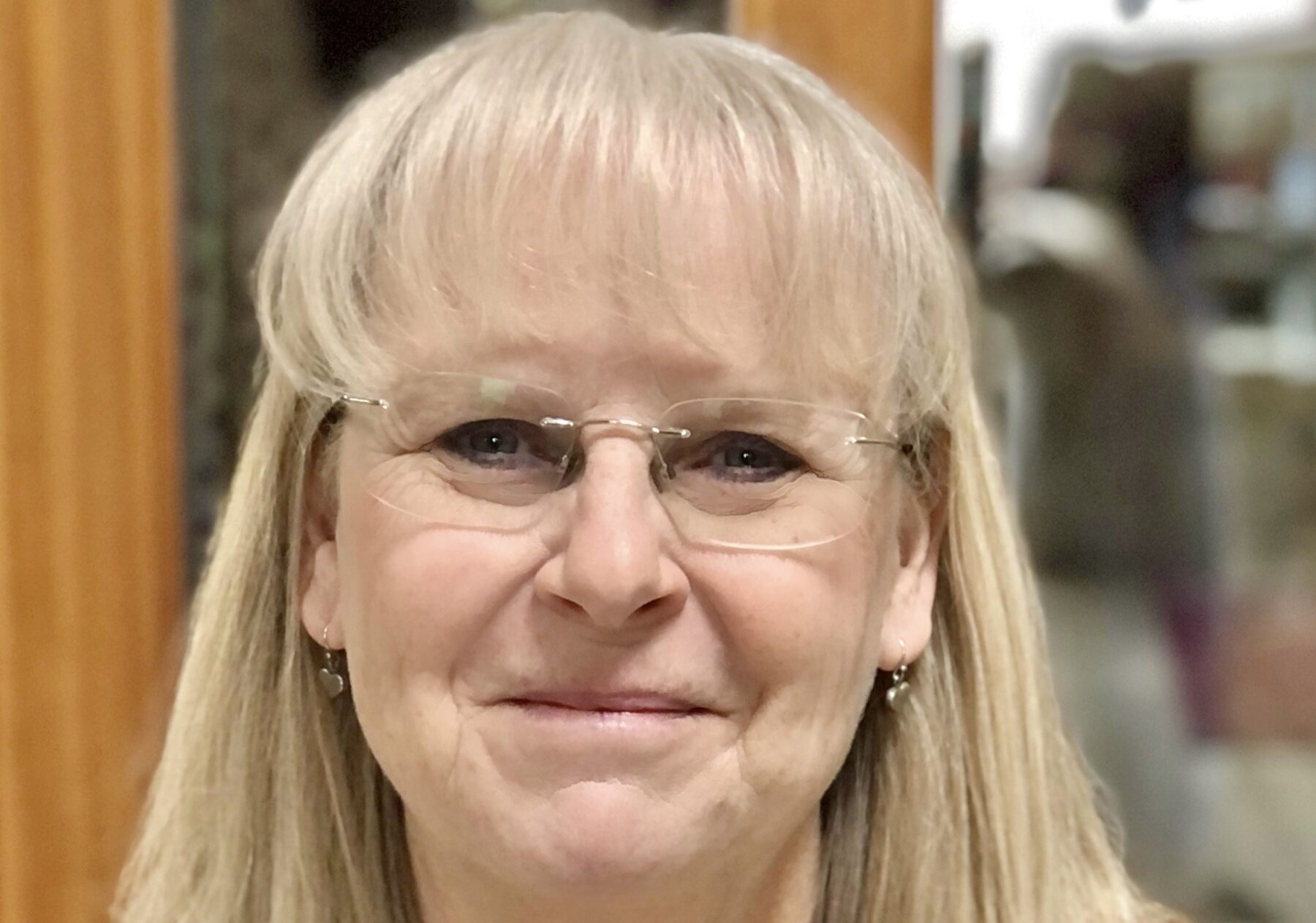 A headshot features an older woman with blond hair and glasses.