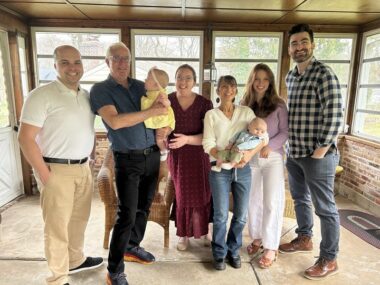 Jodi O’Donnell-Ames is pictured surrounded by family, from left: son-in-law Jared Nespoli; husband Warren Benton Ames holding grandchild Quinn Nespoli; daughter Nora Nespoli; Jodi O’Donnell-Ames holding grandchild Ronan Powers; daughter Alina O’Donnell; and son-in-law Don Powers. (Courtesy of Jodi O’Donnell-Ames)